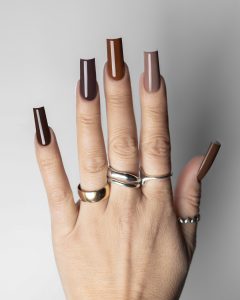 Mão com unhas pintadas de verniz gel castanho chocolate com tons diferentes