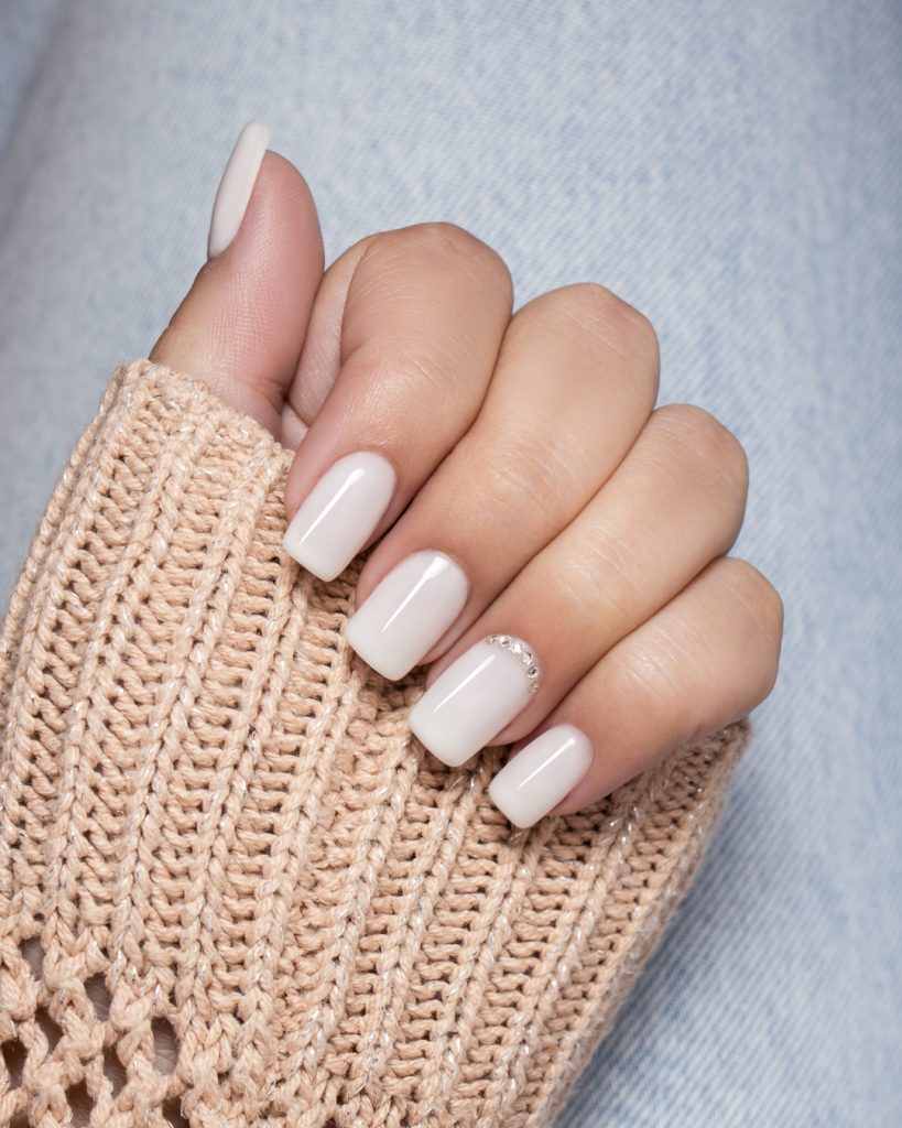 Mão com unhas minimalistas pintadas com verniz gel da coleção milky dancers