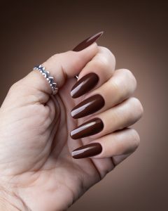 Mão com unhas pintadas com verniz gel em tons castanho chocolate
